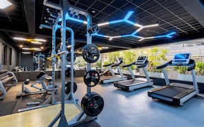 A modern gym with treadmills, weight machines, and a variety of free weights.