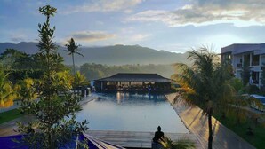 Un resort con piscina, palmeras y montañas al fondo.