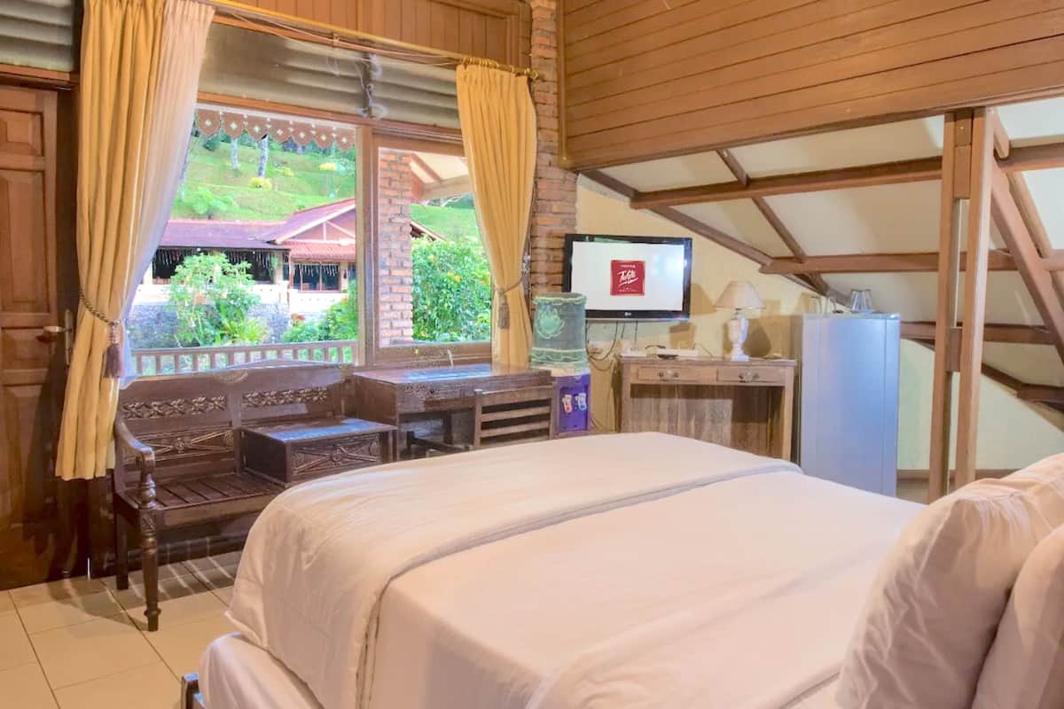 Quarto com cama, escrivaninha de madeira e televisão.