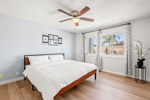 A bedroom with a bed, ceiling fan, window with curtains, and a potted plant. - Near ONT Ontario Oasis Designer Home w Garden Park (Ontario)