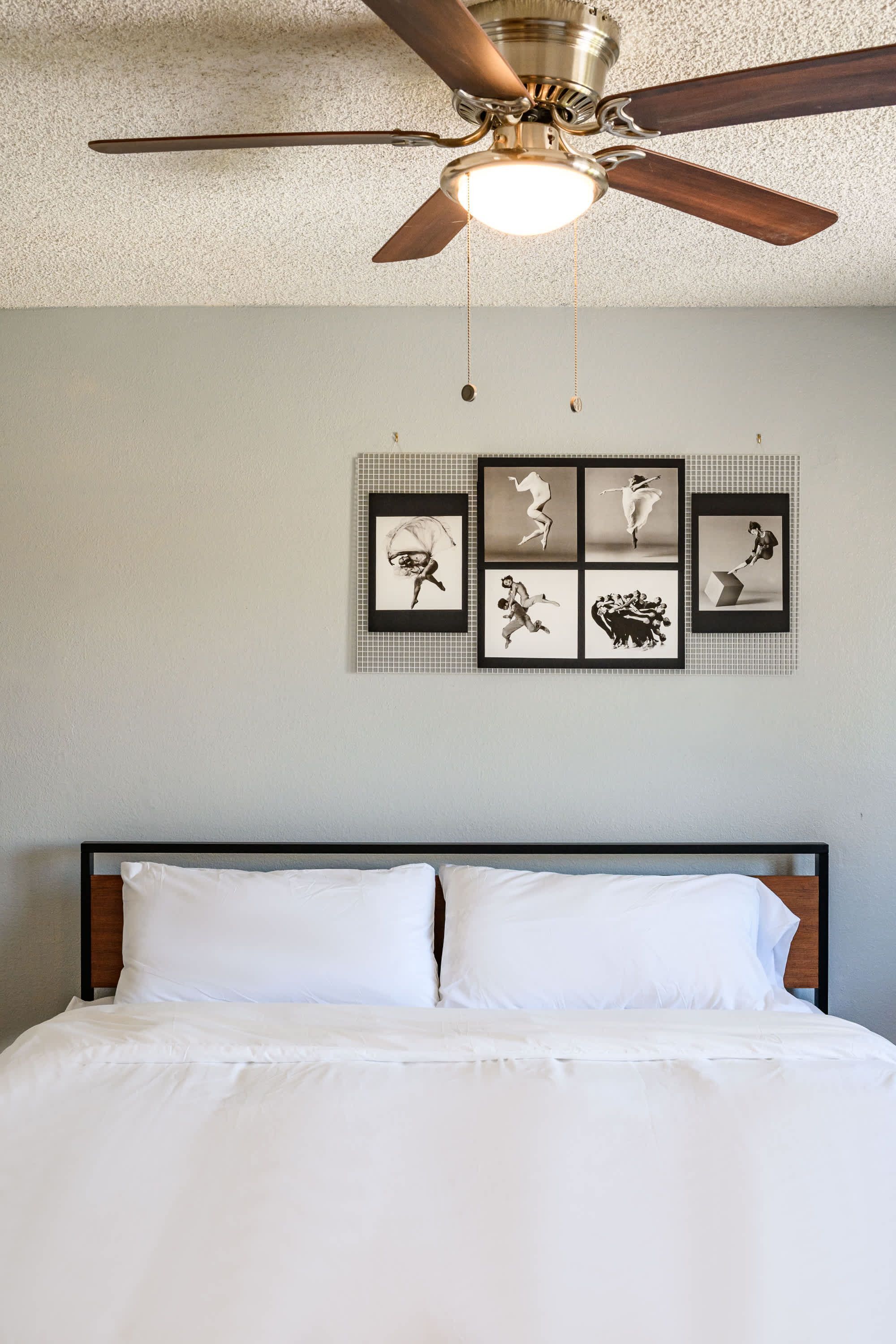 Une chambre à coucher avec un lit, un ventilateur de plafond et des œuvres d’art murales.