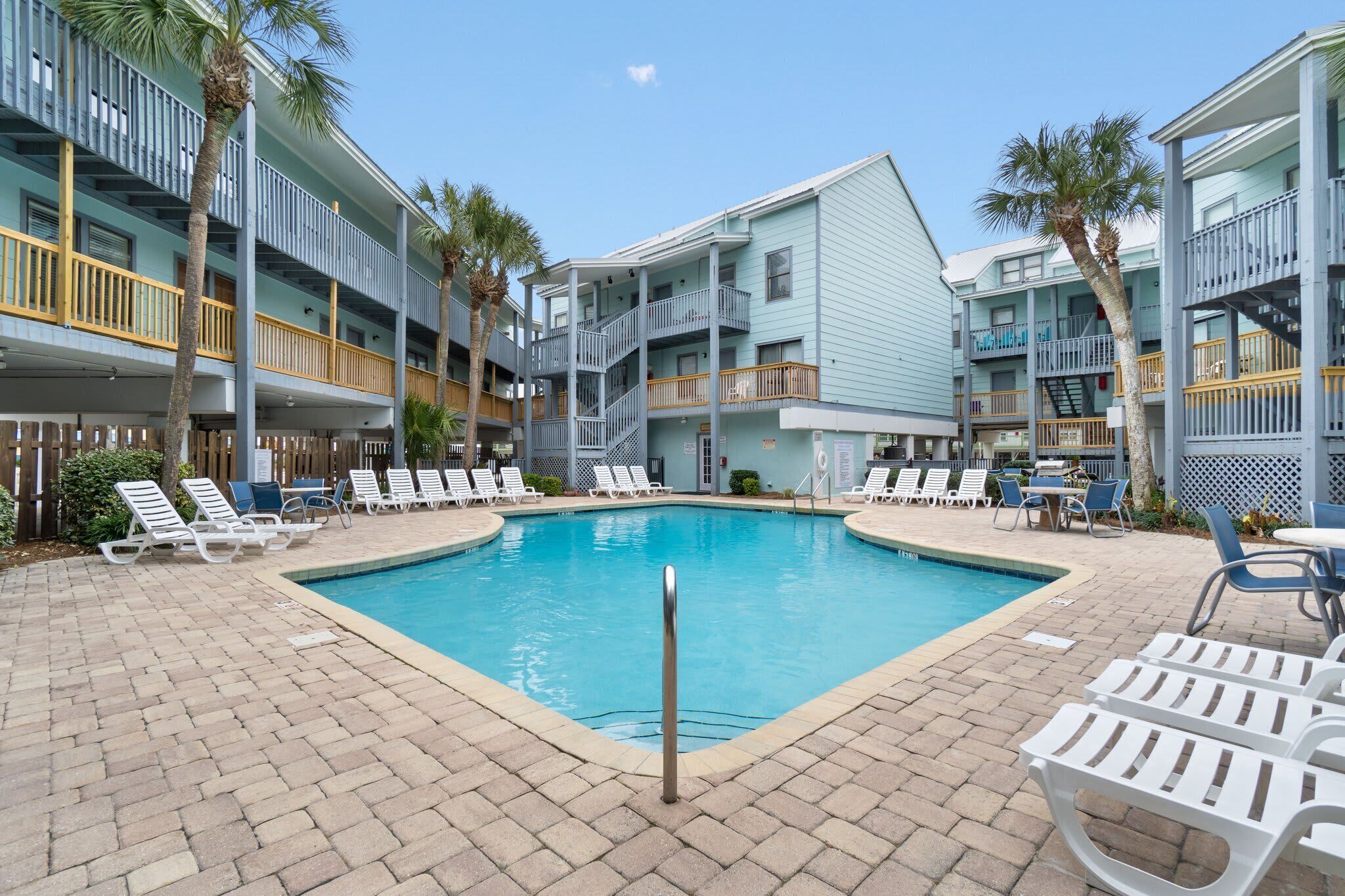 A pool area with lounge chairs and a building with multiple balconies.