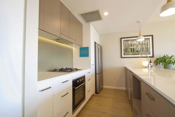 Una cocina moderna con armarios blancos, electrodomésticos de acero inoxidable y piso de madera.