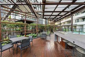 Una terrazza esterna con pavimento in legno, ringhiere in metallo e tavoli e sedie.