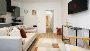 A modern living room with a sofa, a coffee table, and a TV mounted on the wall. - Modern & Cosy 2 Bed Flat in Charming Roath (Cardiff)