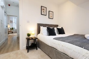 Une chambre à coucher avec un lit, une table de chevet, une lampe et deux tableaux encadrés accrochés au mur.