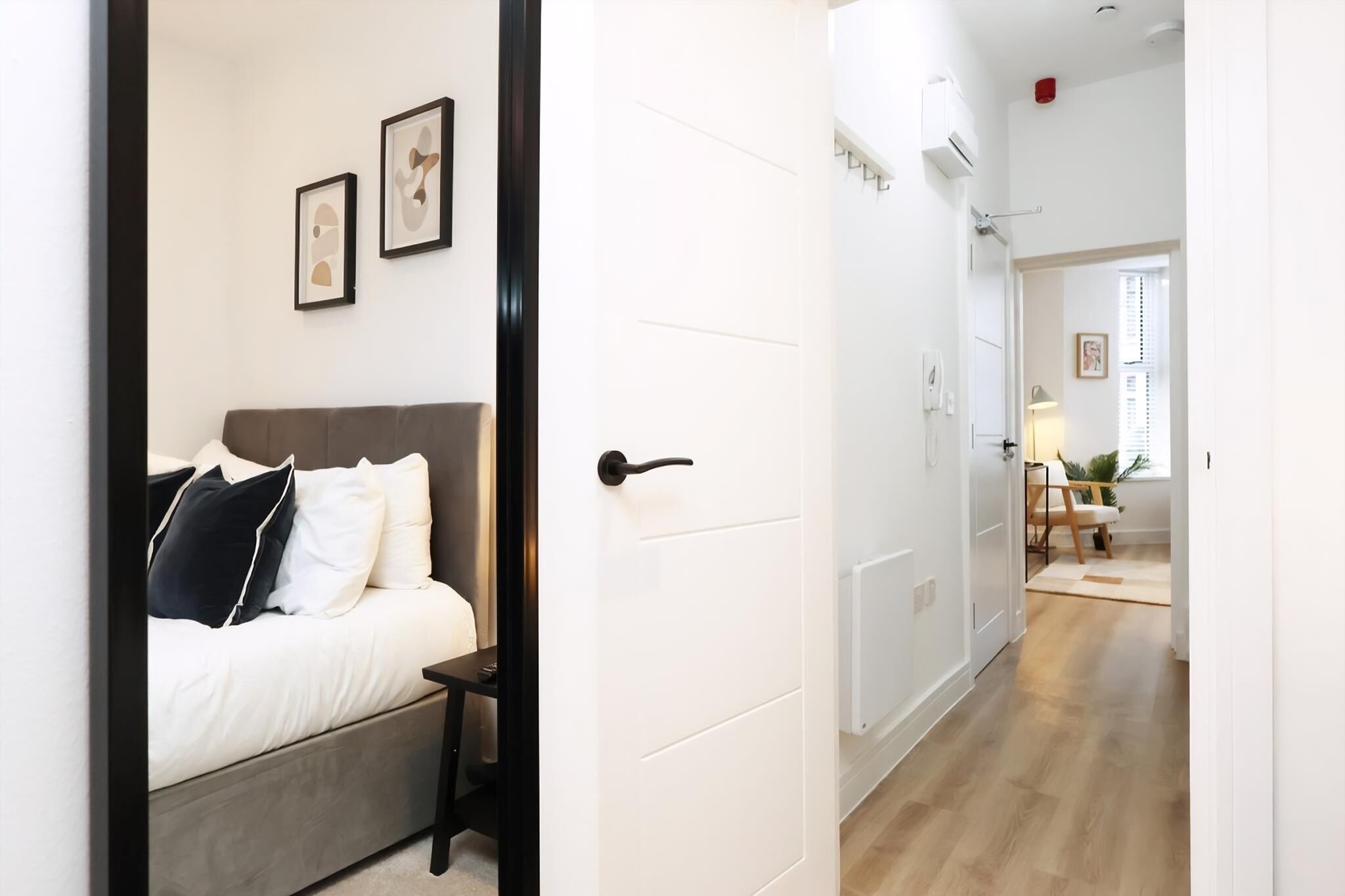 A bedroom with a bed, bedside table, and wall-mounted artwork.