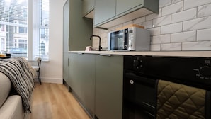 A compact kitchen with grey cabinets, a microwave, and a dishwasher. - Modern & Cosy 2 Bed Flat in Charming Roath (Cardiff)