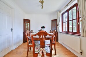 Un comedor con sillas de madera, una mesa y una ventana con cortinas.