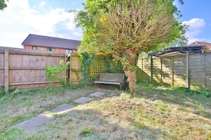 A backyard with a wooden fence, a bench, and a tree. - Homely 5 Bed House - 15 Mins to Cardiff City (Cardiff)