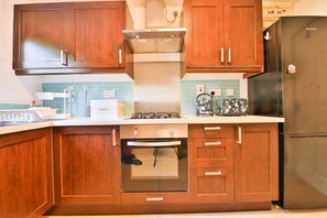 A kitchen with wooden cabinets, a stainless steel refrigerator, a built-in oven, and a gas stove. - Homely 5 Bed House - 15 Mins to Cardiff City (Cardiff)