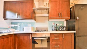 Une cuisine dotée de meubles en bois, d’un réfrigérateur en acier inoxydable, d’un four encastré et d’une cuisinière à gaz.