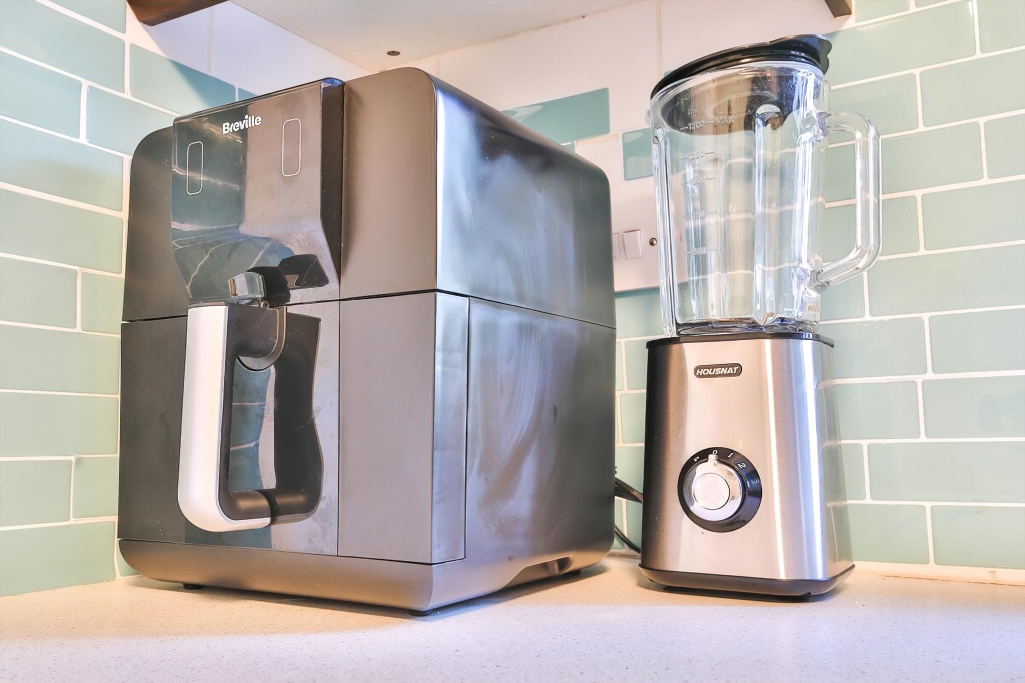 A Breville coffee maker and a Housmat blender on a kitchen counter.