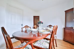 Uma sala de jantar com mesa de madeira, cadeiras e um armário.