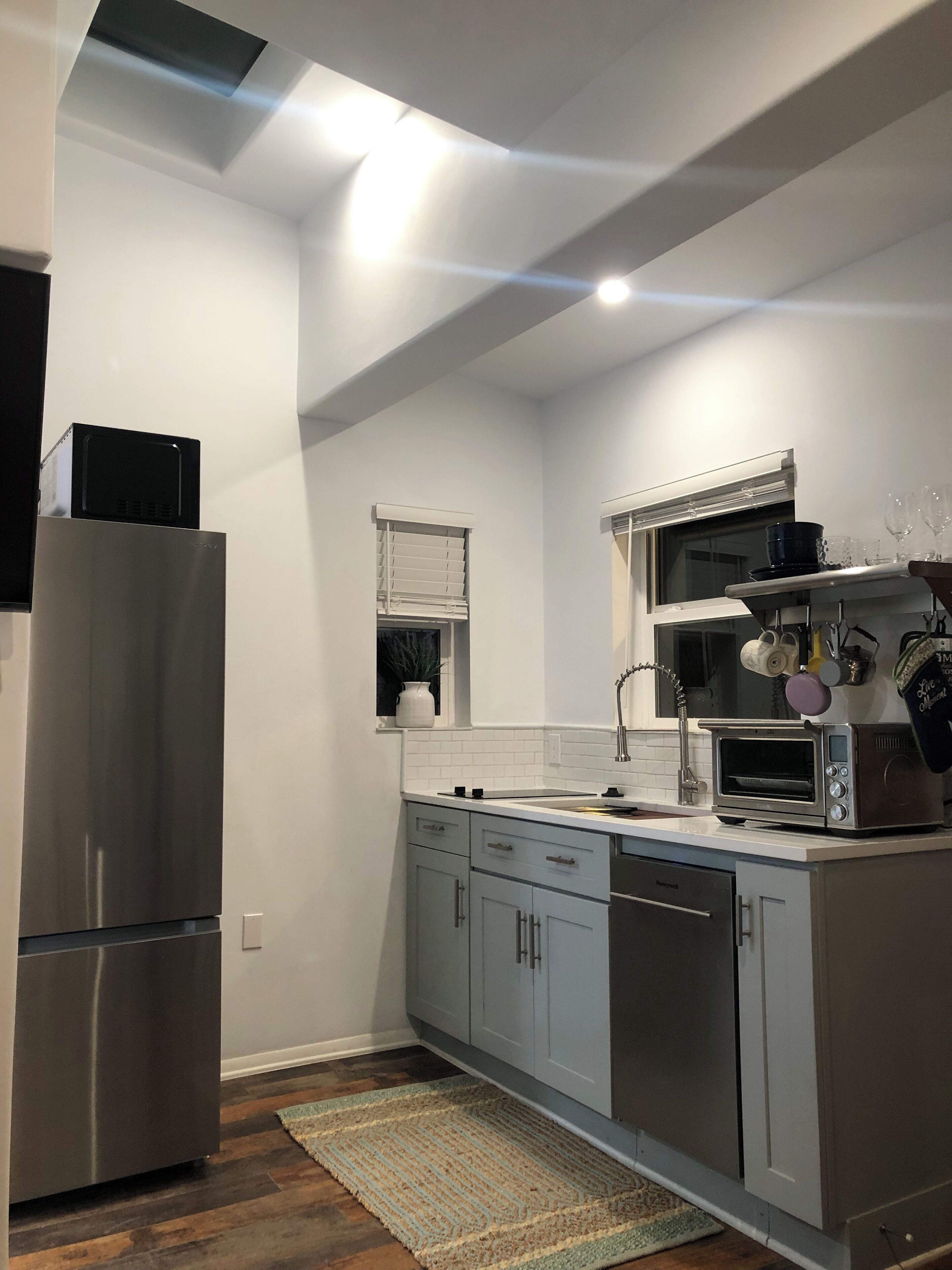 Een moderne keuken met roestvrijstalen apparatuur, een inbouwoven en een raam met zonwering.