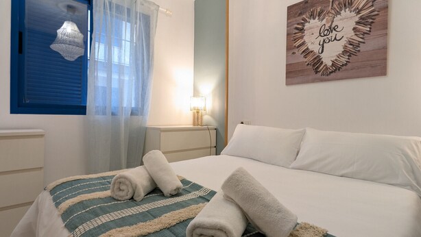 A neatly made bed with rolled towels, a decorative wall piece, and a hanging light fixture in a hotel room. - 25 - Livingtarifa The Island (Tarifa)
