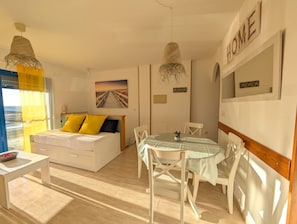 A bedroom with a bed, bedside table, and a view of the sea.