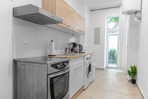 Cozinha moderna com forno embutido, micro-ondas e máquina de lavar louça. Possui bancada de madeira e janela que permite entrada de luz natural.