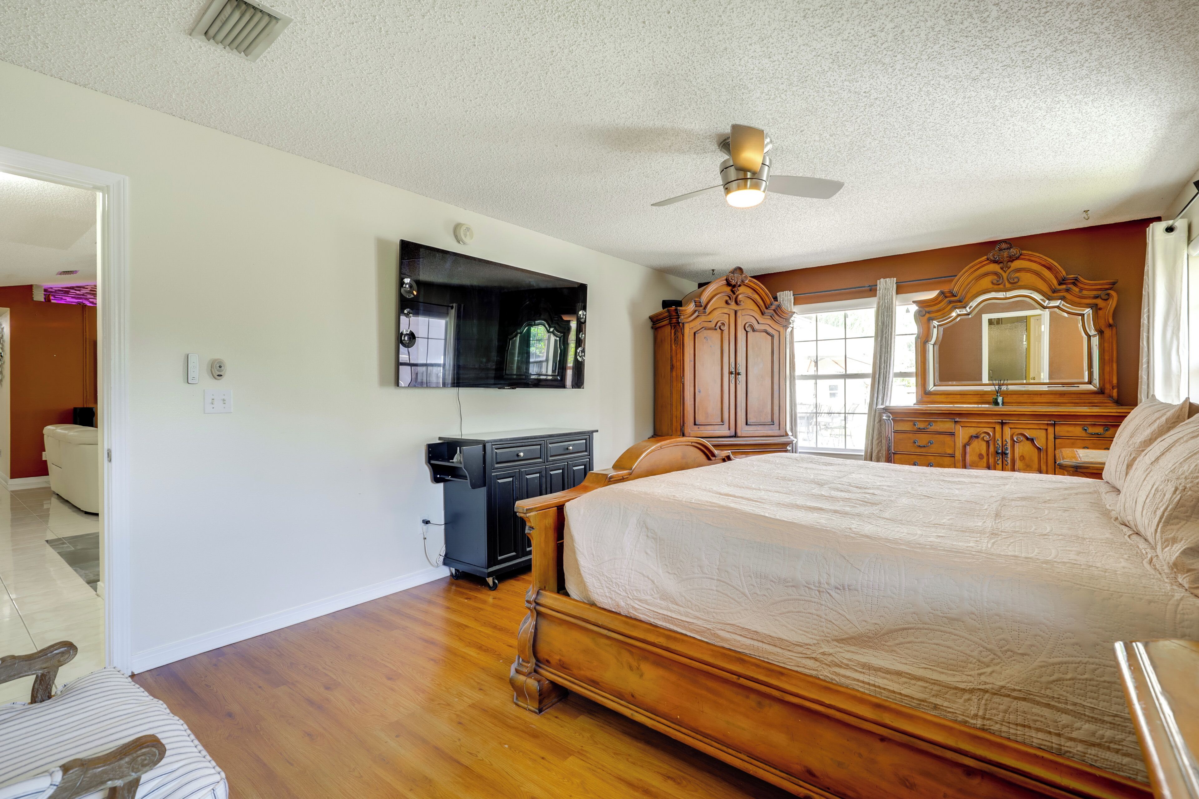 A bedroom with a large bed, wooden wardrobe, and a ceiling fan.