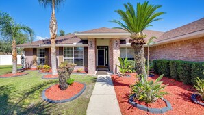 A two-story house with a brick exterior, a front porch, and a landscaped garden with palm trees and red mulch. - Backyard Oasis w/ Private Pool: Jacksonville Gem (Jacksonville)