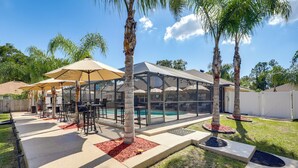 A covered outdoor patio with a pool, palm trees, and outdoor furniture. - Backyard Oasis w/ Private Pool: Jacksonville Gem (Jacksonville)