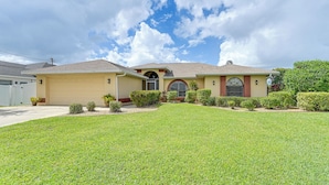 A two-story house with a garage, a well-maintained lawn, and a clear sky. - Waterfront Cape Coral Home: Views & Birdwatching (Cape Coral)