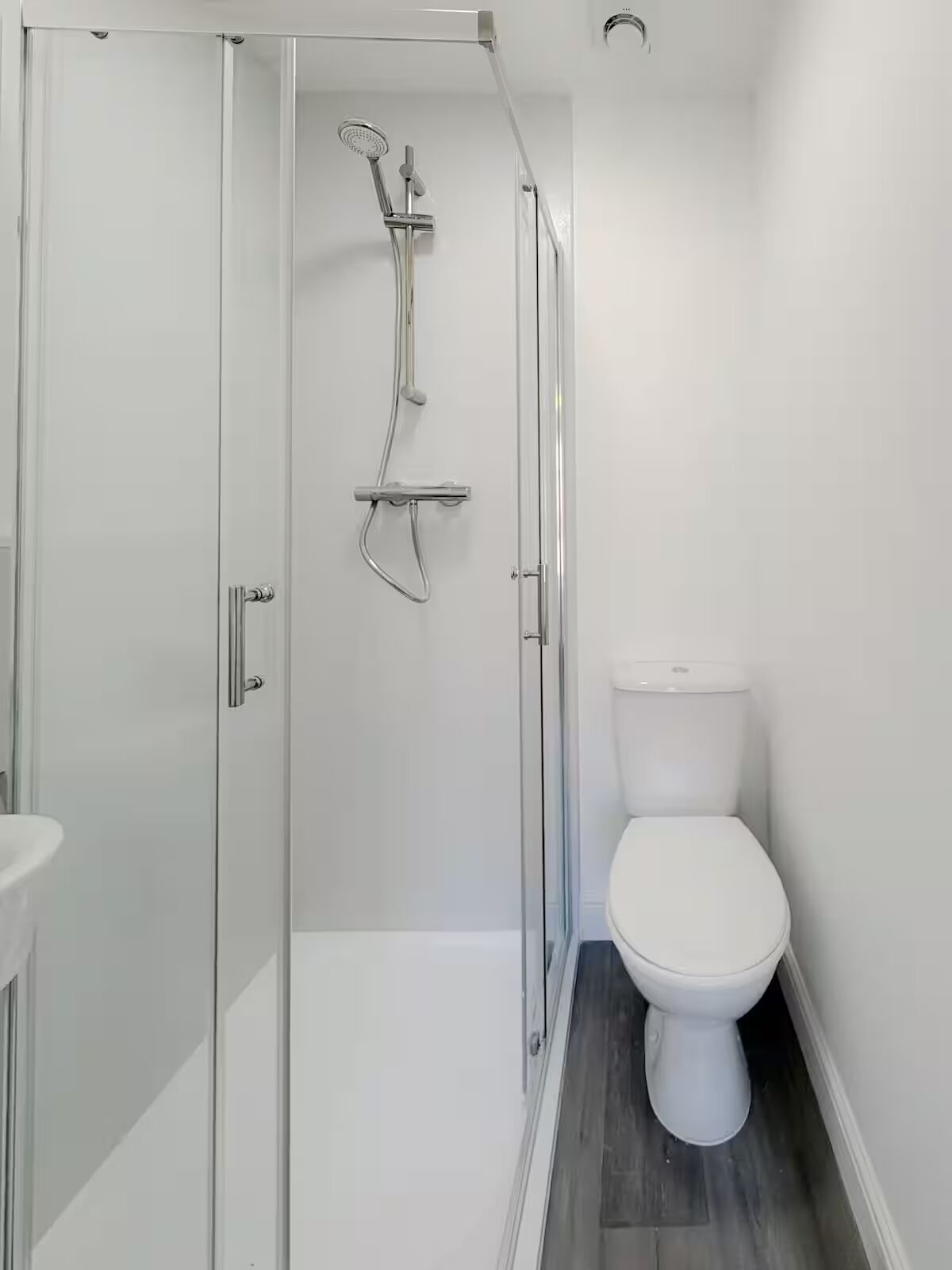 A modern bathroom with a glass-enclosed shower, a white toilet, and a sink.