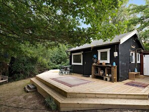 A wooden deck with a small table and chairs, a wooden bench, and a rug.