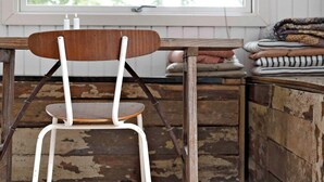 A rustic wooden chair with a metal frame, positioned in front of a window with a view of trees.