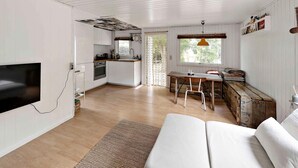 A compact, modern kitchen with white cabinetry, a built-in oven, and a window above the sink.