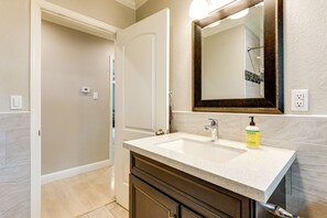 A bathroom with a white sink, dark cabinetry, a mirror, and a bottle of soap. - Walkable Location! Sacramento Home w/ Patio (Sacramento)