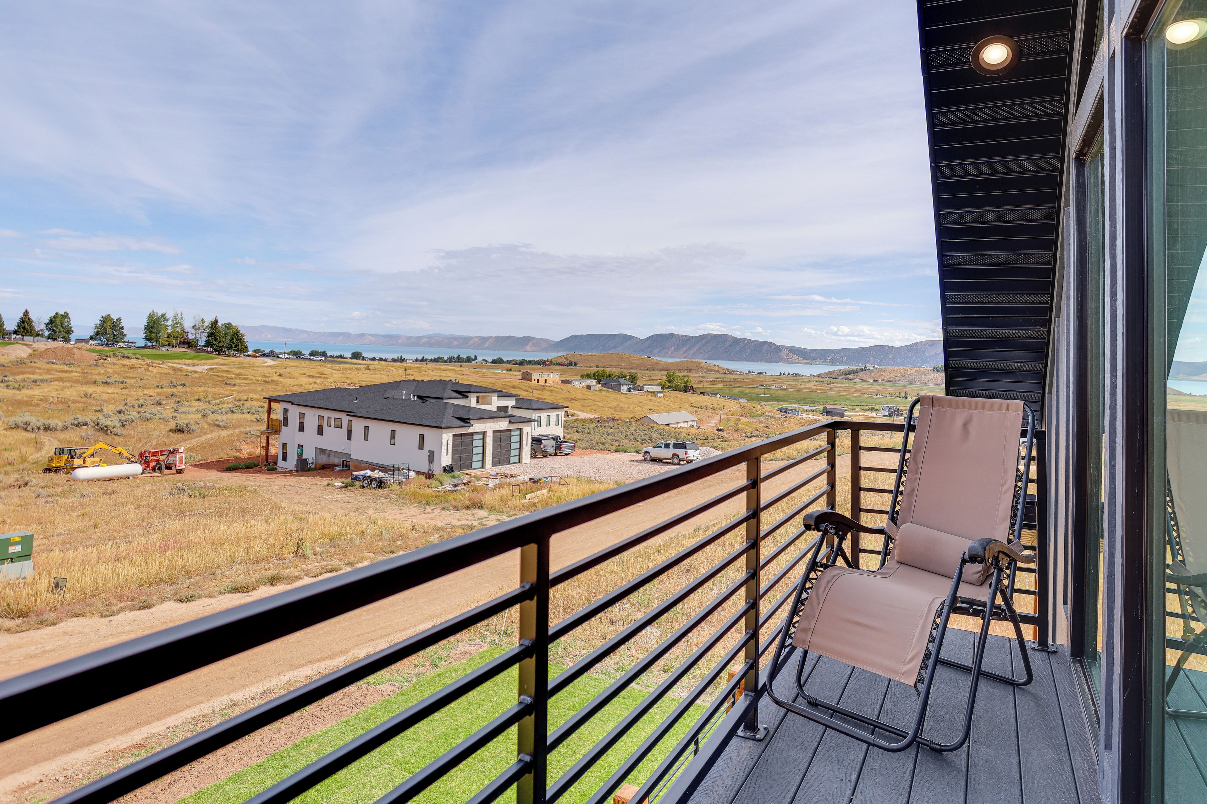 A balcony with a view of a construction site, a modern house, and a mountainous landscape.