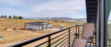 A balcony with a view of a construction site, a modern house, and a mountainous landscape.