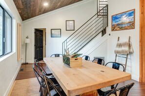 A dining area with a wooden table, chairs, a staircase, and a view of the outdoors. - Mid-mod Mountain Cabin Near Thumb Butte Trails! (Prescott)