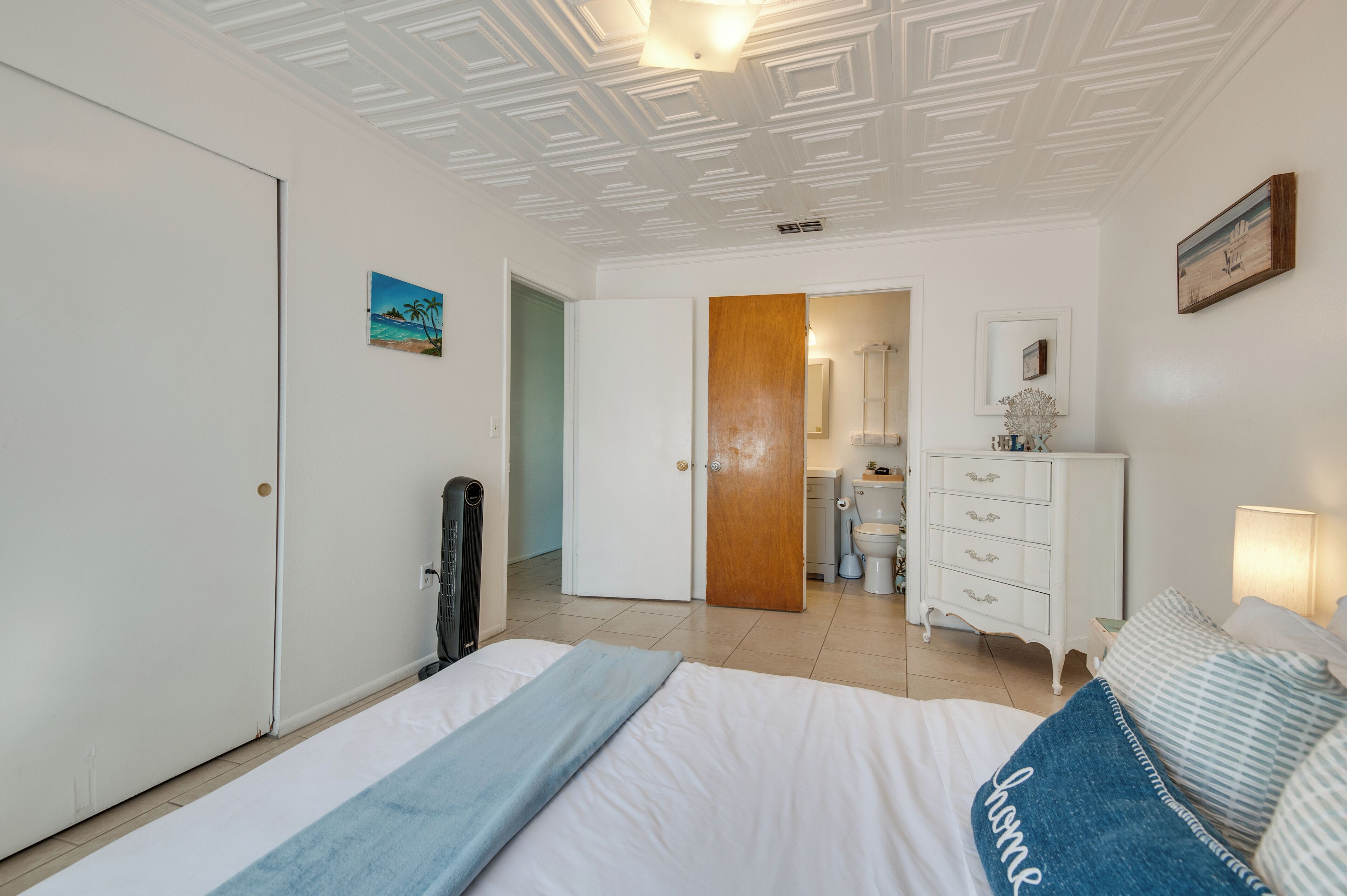 Una camera da letto con un letto, una cassettiera, uno specchio e una porta che dà su un bagno.