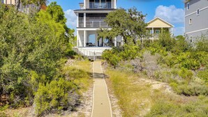 A coastal property with a multi-level house, a pathway leading to the entrance, and surrounding vegetation. - Steps to Shore: Luxe Group Retreat in Port St Joe (Port St. Joe)