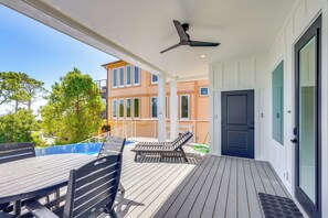 A covered outdoor area with a table and chairs, a ceiling fan, and a view of a building with multiple windows. - Steps to Shore: Luxe Group Retreat in Port St Joe (Port St. Joe)