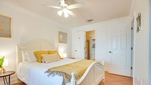 Ein Schlafzimmer mit Bett, Deckenventilator und einer Badezimmertür.