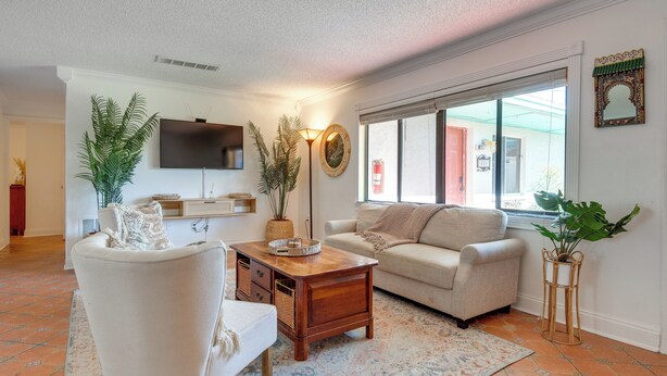 Ein Wohnzimmer mit Sofa, Sesseln, Couchtisch und Zimmerpflanzen.
