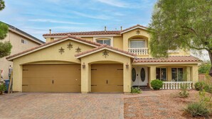 A two-story house with a garage, a balcony, and a landscaped front yard. - Grand & Convenient Home 7 Mi to Las Vegas Strip! (Las Vegas)