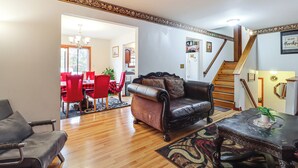 A living room with a leather sofa, a dining area with red chairs, and a staircase. - < 1 Mi to Lake: Family Home in Albrightsville! (Albrightsville)