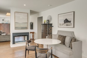 A living room with a fireplace, a sofa, a dining table with chairs, and artwork on the walls. - 7 Mi to Dtwn & Lake Erie: Sleek Cleveland Apt! (Cleveland)