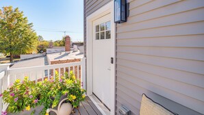 A residential building with a white exterior, a visible door, and a small balcony with potted plants. - 7 Mi to Dtwn & Lake Erie: Sleek Cleveland Apt! (Cleveland)