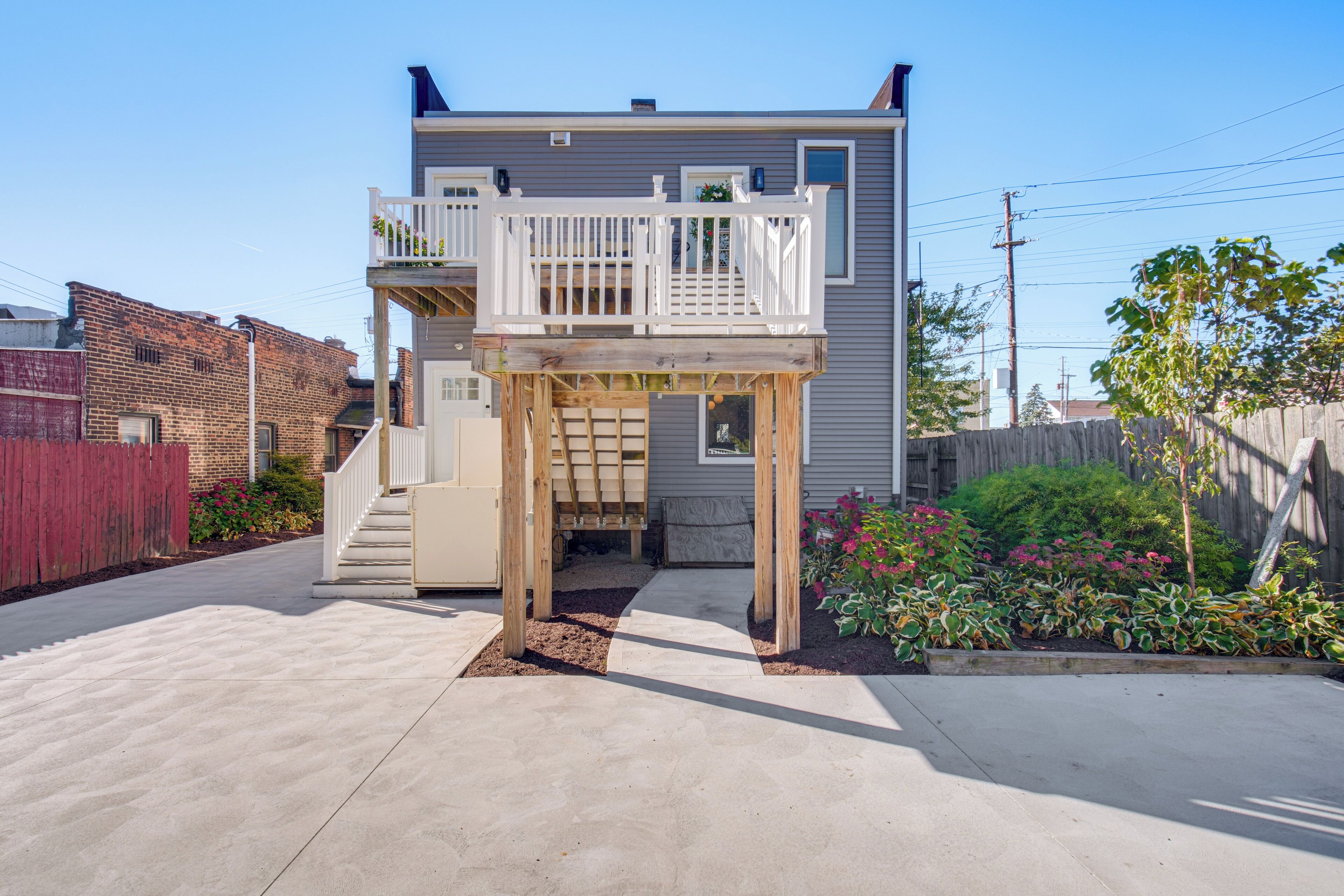 A two-story house with a wooden deck and a small front yard.
