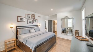 A bedroom with a wooden bed, a bedside table, a mirror, and framed pictures on the wall. - 7 Mi to Dtwn & Lake Erie: Sleek Cleveland Apt! (Cleveland)
