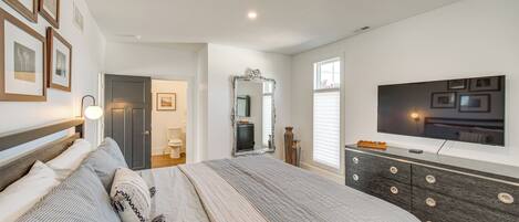 A bedroom with a large bed, a dresser, a TV, and framed pictures on the wall.
