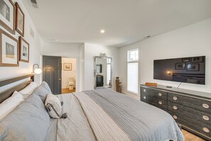 Un dormitorio con una cama grande, un aparador, un televisor y cuadros en la pared.