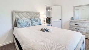 Een slaapkamer met een bed, een kaptafel en een deur naar een andere kamer.