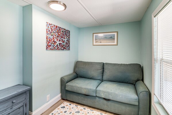 A room with a grey sofa, a small wooden cabinet, a patterned rug, and two wall decorations. - 5 Mi to Manatees! Waterfront Crystal River Home (Crystal River)