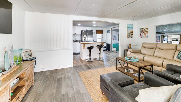 A modern living room with a leather sofa, a wooden coffee table, and a kitchen area in the background. - 2 Mi to Beach! Canal-front Escape in Crystal River (Crystal River)